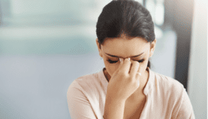 A woman holding her head in front of her face.