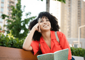 A woman sitting on top of a bench with her hand under her chin.